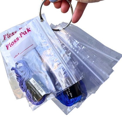 Clear plastic bag with blue thread and a keychain, labeled &