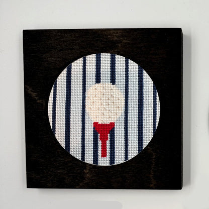 gold ball on a tee needlepoint ornament in a black frame