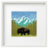 Framed cross-stitched artwork of a mountain landscape with a bison.