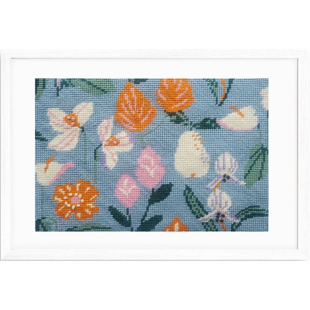 Framed needlepoint with colorful floral pattern on a blue background