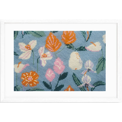 Framed needlepoint with colorful floral pattern on a blue background