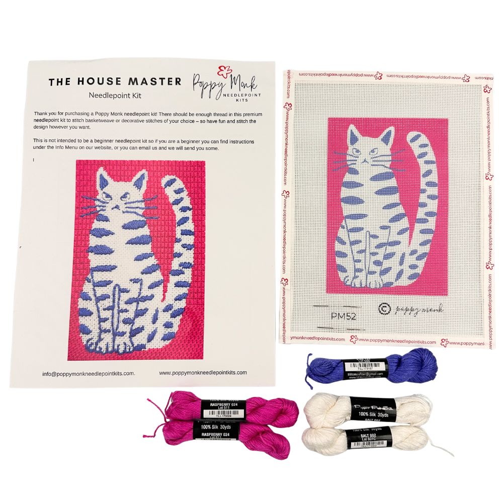 Needlepoint kit with cat design, yarn, and packaging on a white background