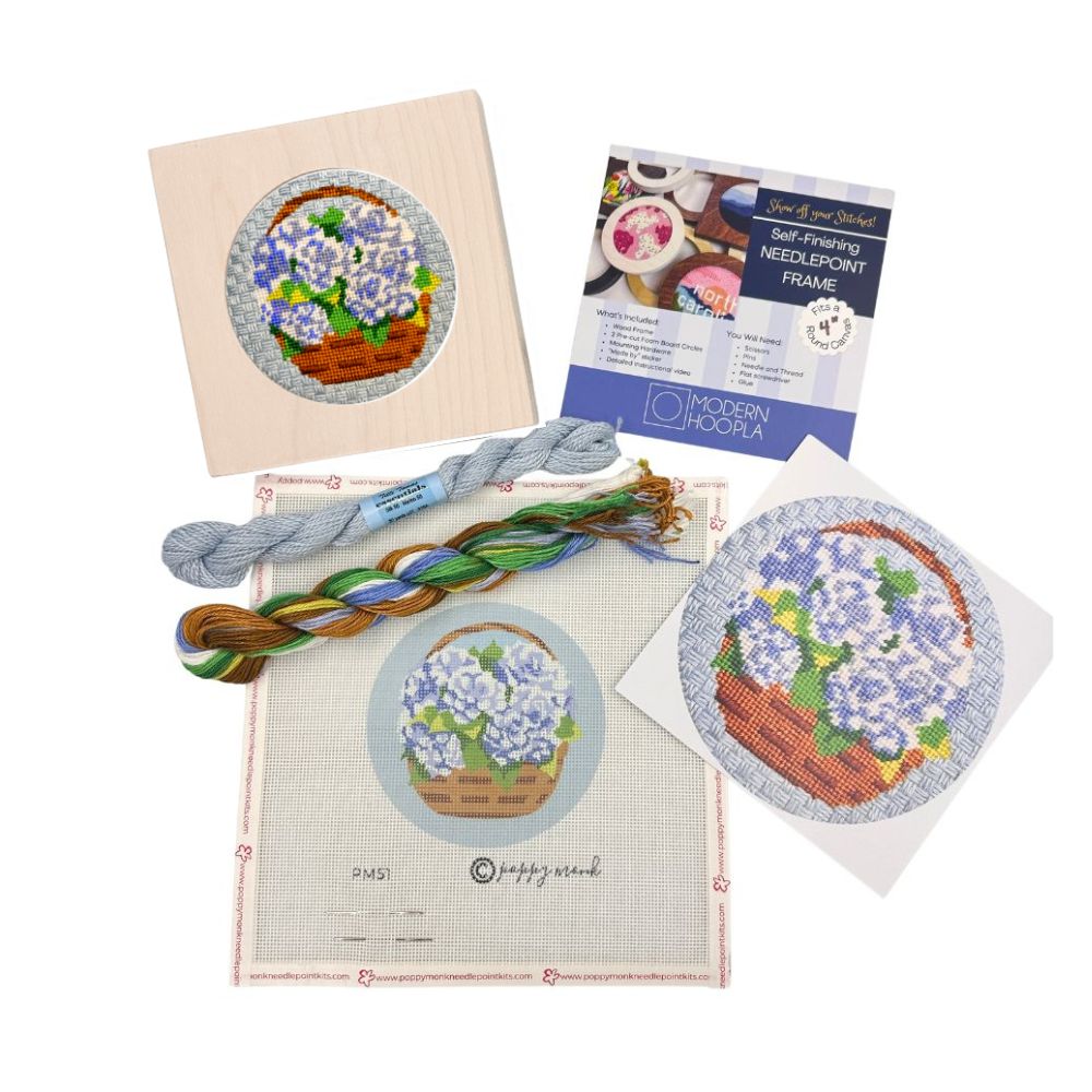Needlepoint kit with pre-printed patterns, threads, and a frame on a white background