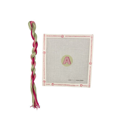 Braided pink and green yarn with a package on a white background