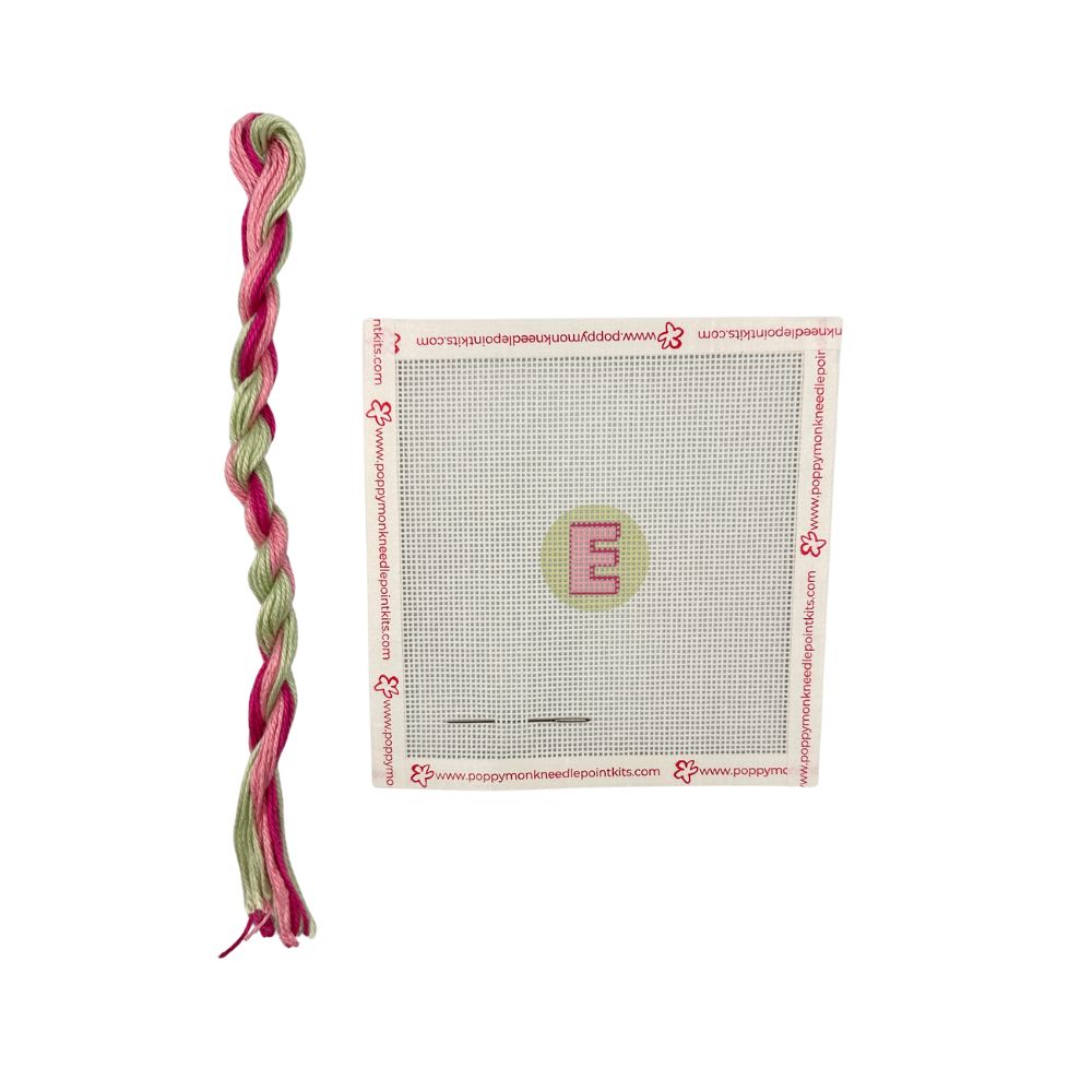 Pink and green braided toy with a packaging sheet featuring a letter &