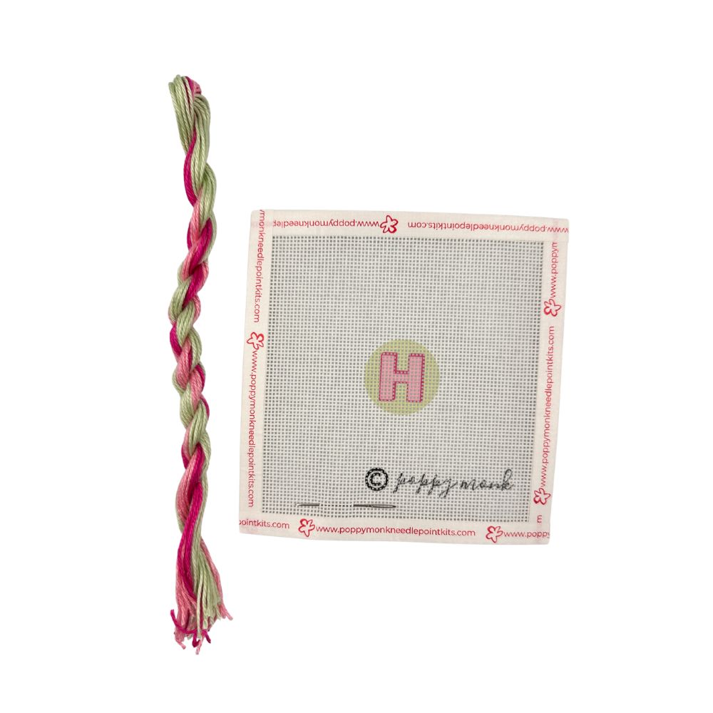 Braided pink and green toy with a branded label on a white background