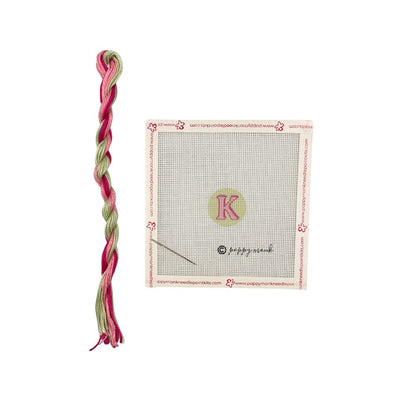 Pink and green braided hair tie with a branded card on a white background