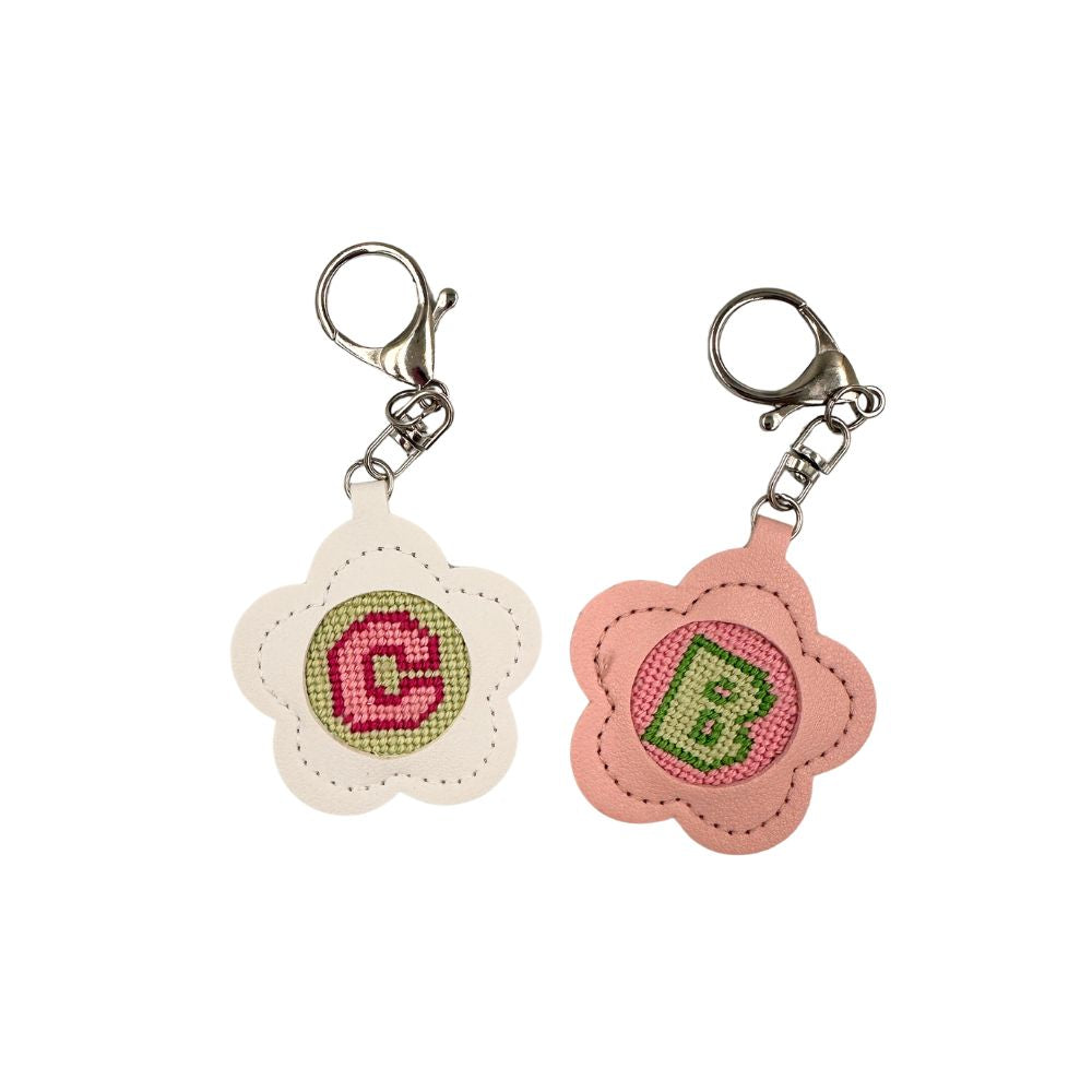 Two floral keychains with embroidered initials on a white background