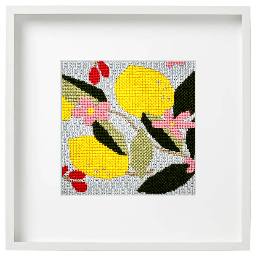 Needlepoint design of two lemons on a branch shown in a white frame