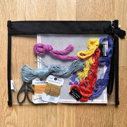 Embroidery thread set with scissors and tools in a clear pouch on a wooden surface