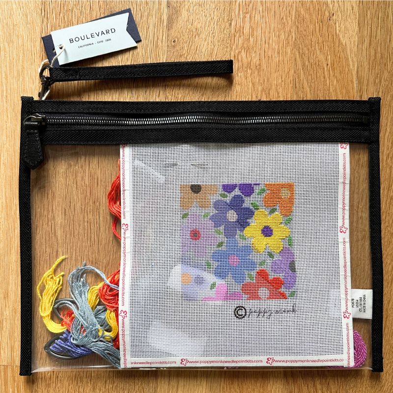 Embroidery kit with colorful flowers on a clear plastic case, on a wooden surface.