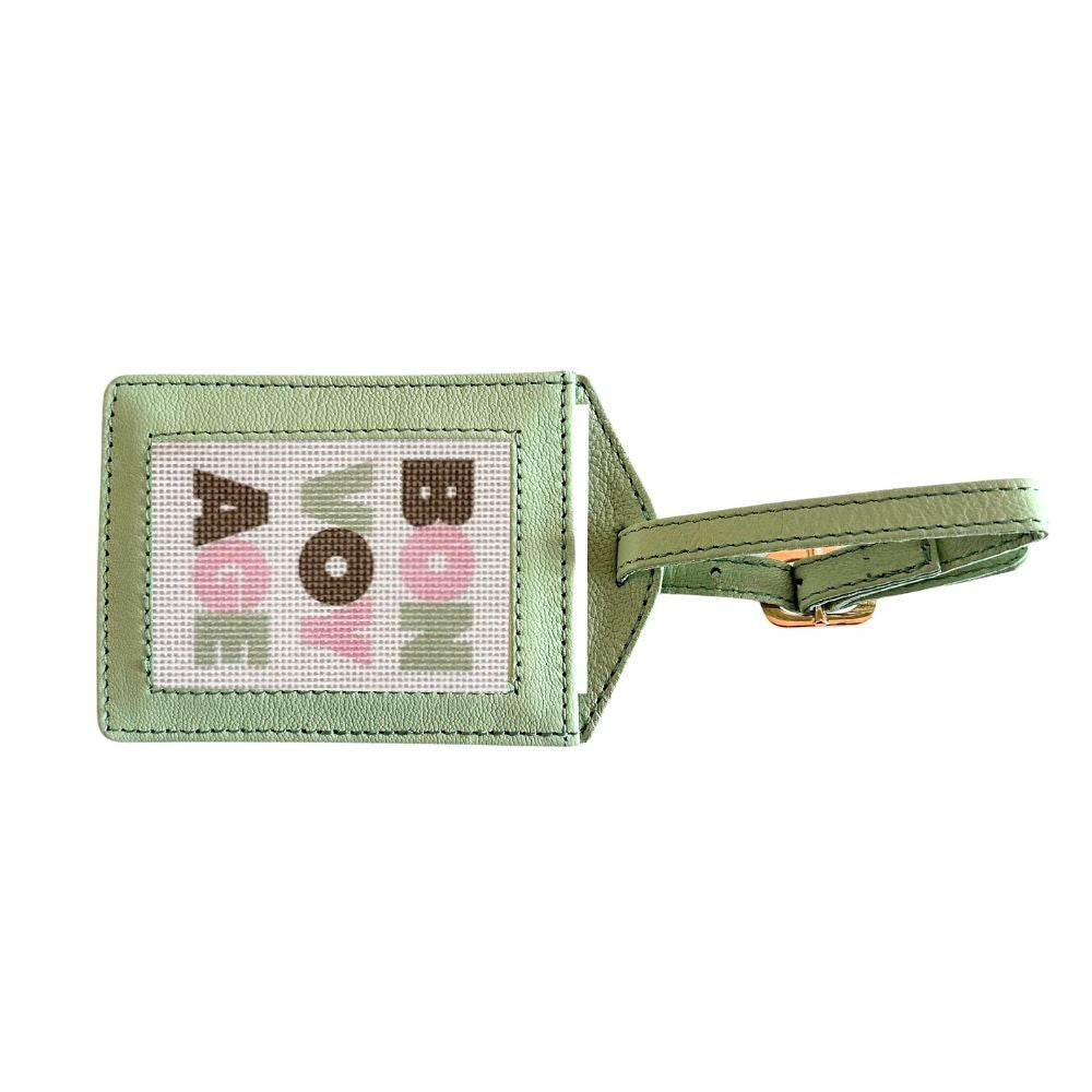 Green luggage tag with colorful text on a white background