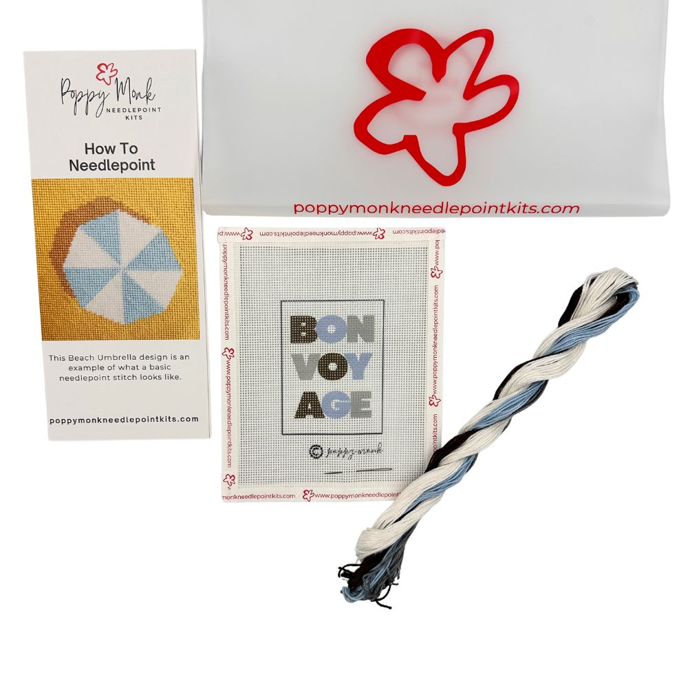 Collection of Poppy Monk needlepoint kit components including a book, canvas, and thread on a white background.