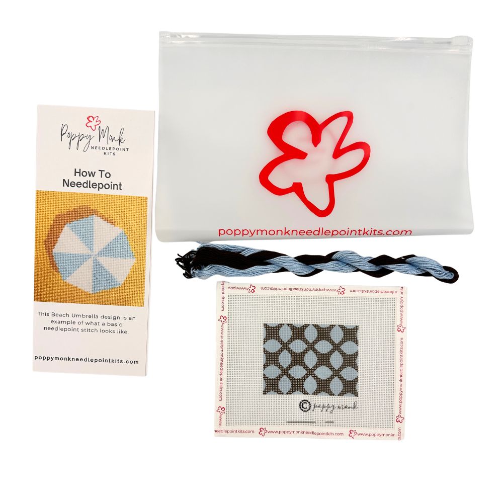 Poppy Monk needlepoint kit with fabric, thread, and pattern guide on a white background