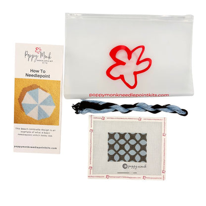 Poppy Monk needlepoint kit with fabric, thread, and pattern guide on a white background