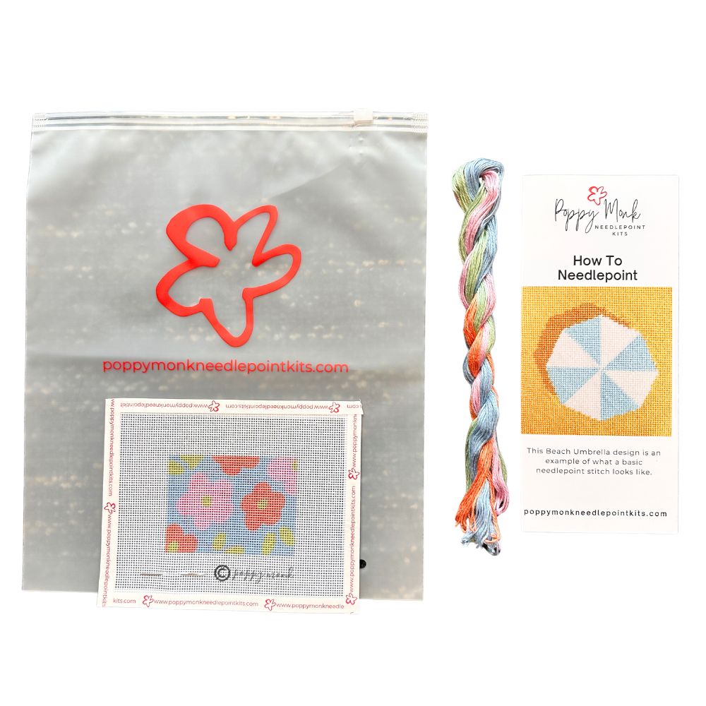 Poppy Monk needlepoint kit with flower design, yarn, and instructional card on a white background
