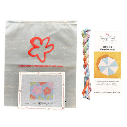 Poppy Monk needlepoint kit with flower design, yarn, and instructional card on a white background