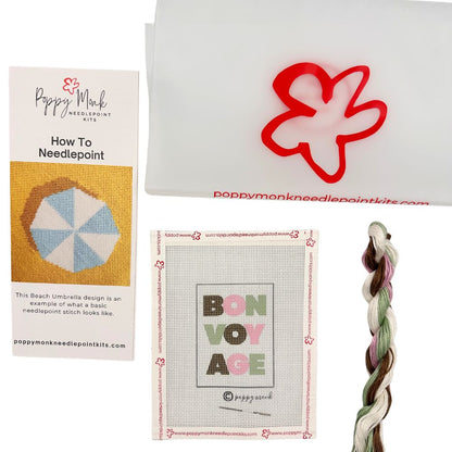 Poppy Monk needlepoint kit with instructions, red flower design, and braid on a white background