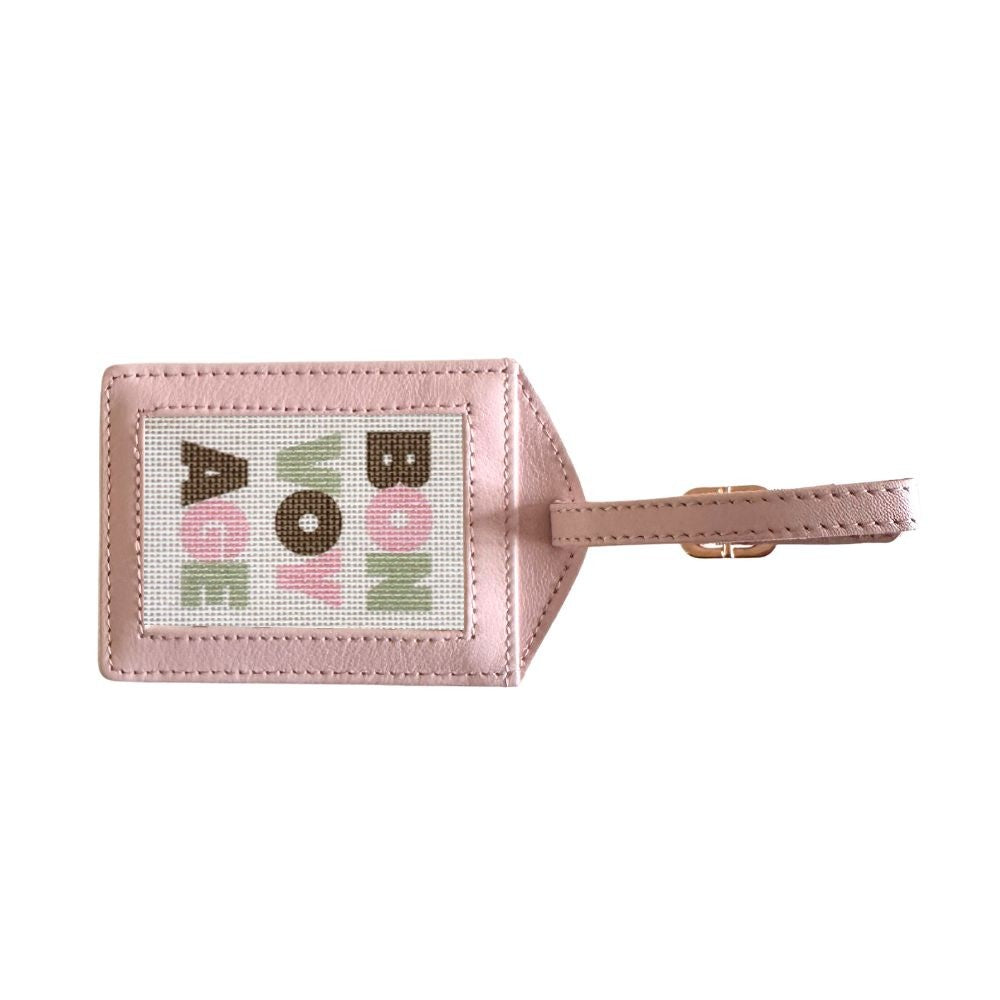 Pink luggage tag with colorful text on a white background