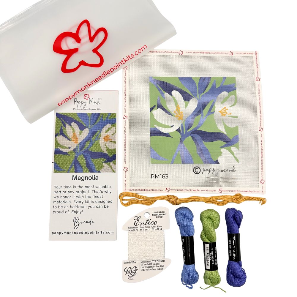 Needlepoint kit with fabric, pattern, floss, and packaging on a white background
