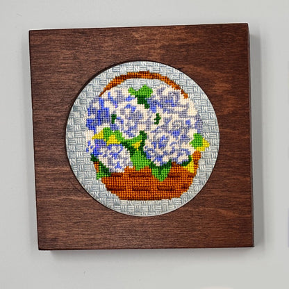 Embroidered basket of flowers on a wooden panel