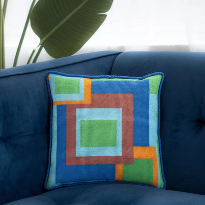Abstract needlepoint pillow shown on a sofa