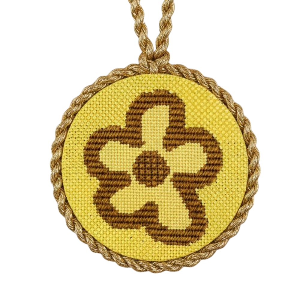 Decorative needlepoint ojrnament with brown floral design and rope border on a white background