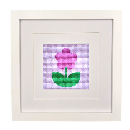 Framed needlepoint flower design on a white background