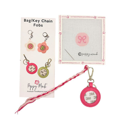 A needlepoint kit with a small round pink bow design with fob hardware.