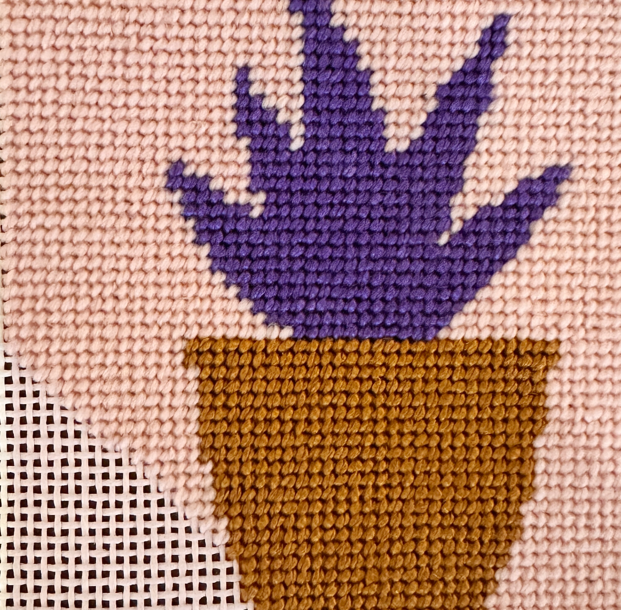 Needlepoint purple plant in a brown pot on beige fabric