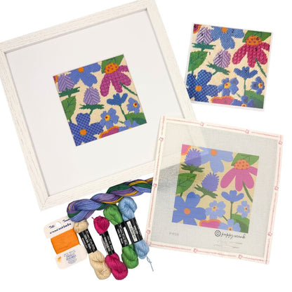 A needlepoint kit with oak wod white frame and a floral design and threads
