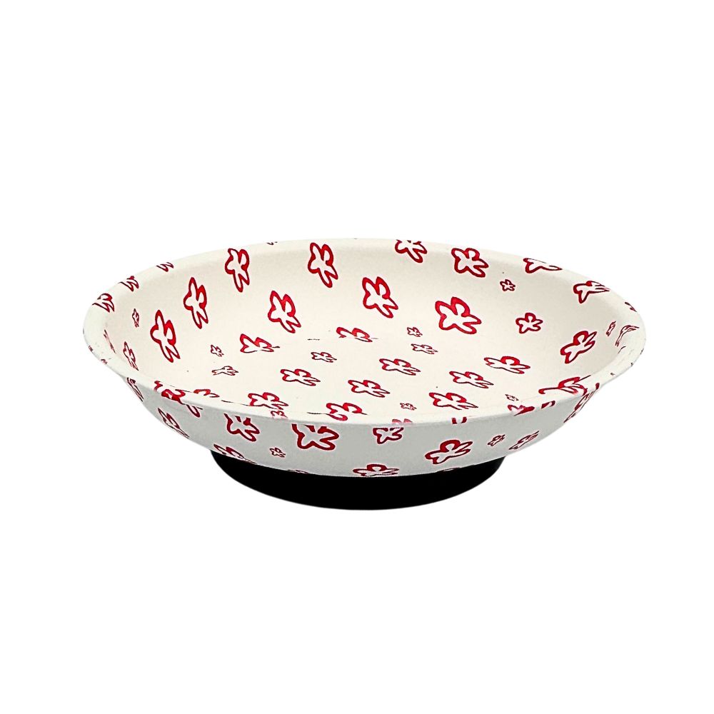 A white bowl with a red floral pattern, displayed on a black stand against a plain white background.
