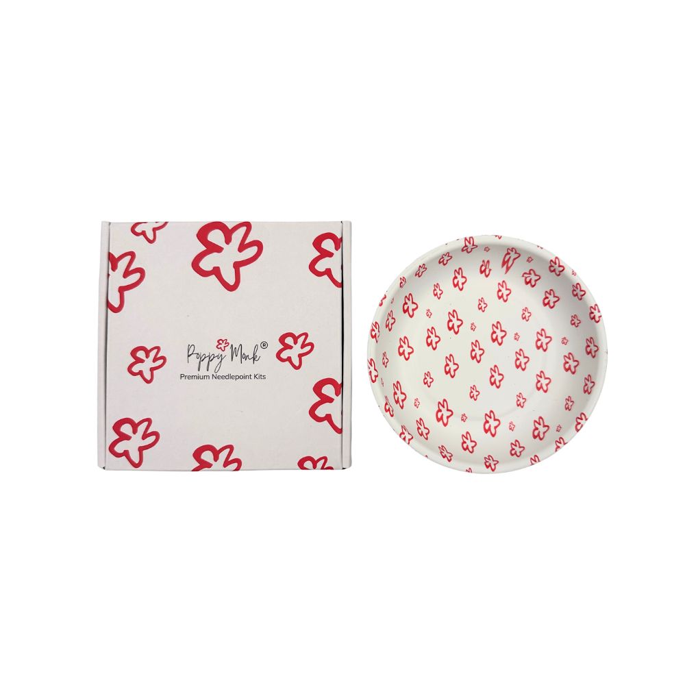 A white dish with a poppy pattern next to a closed box