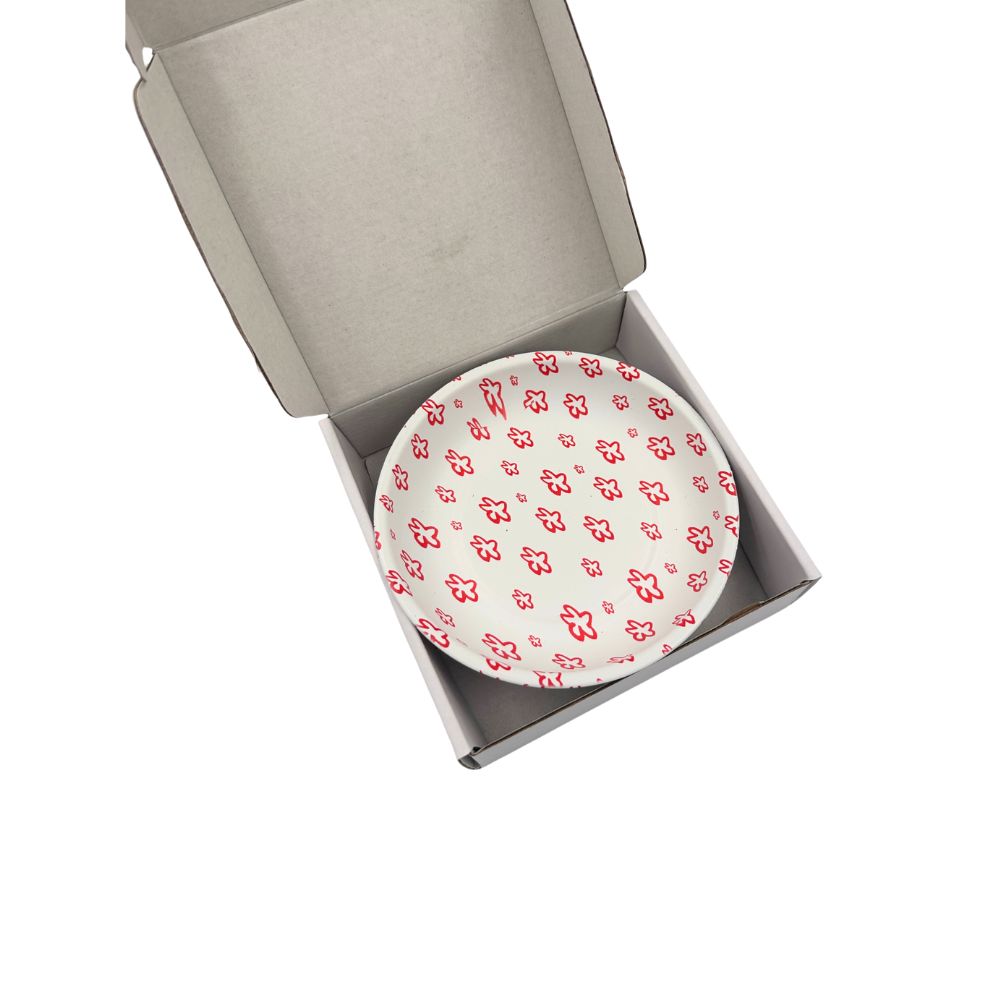 A round white dish with a poppy pattern in an open box