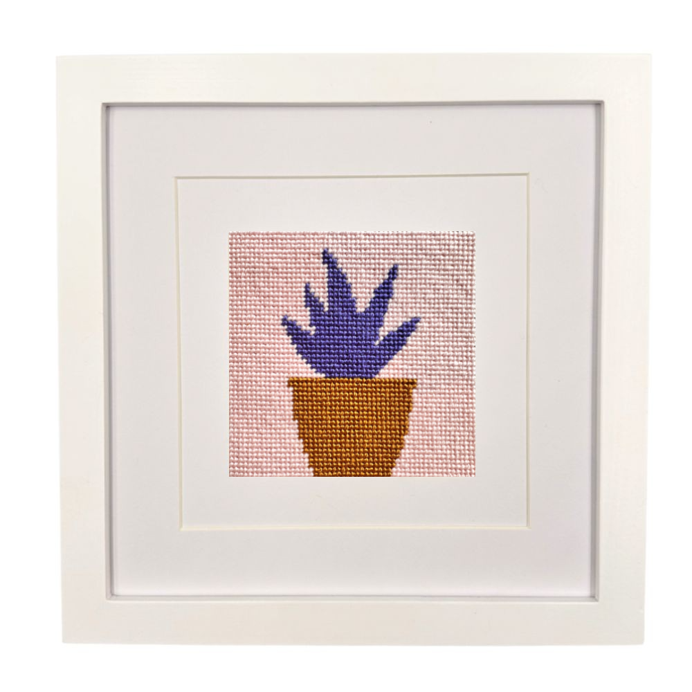 Framed needlepoint artwork of a potted plant on a white background