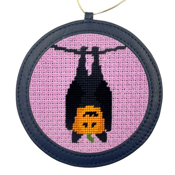 A Halloween needlepoint design of a pumpkin in a bat costume, finished as an ornament