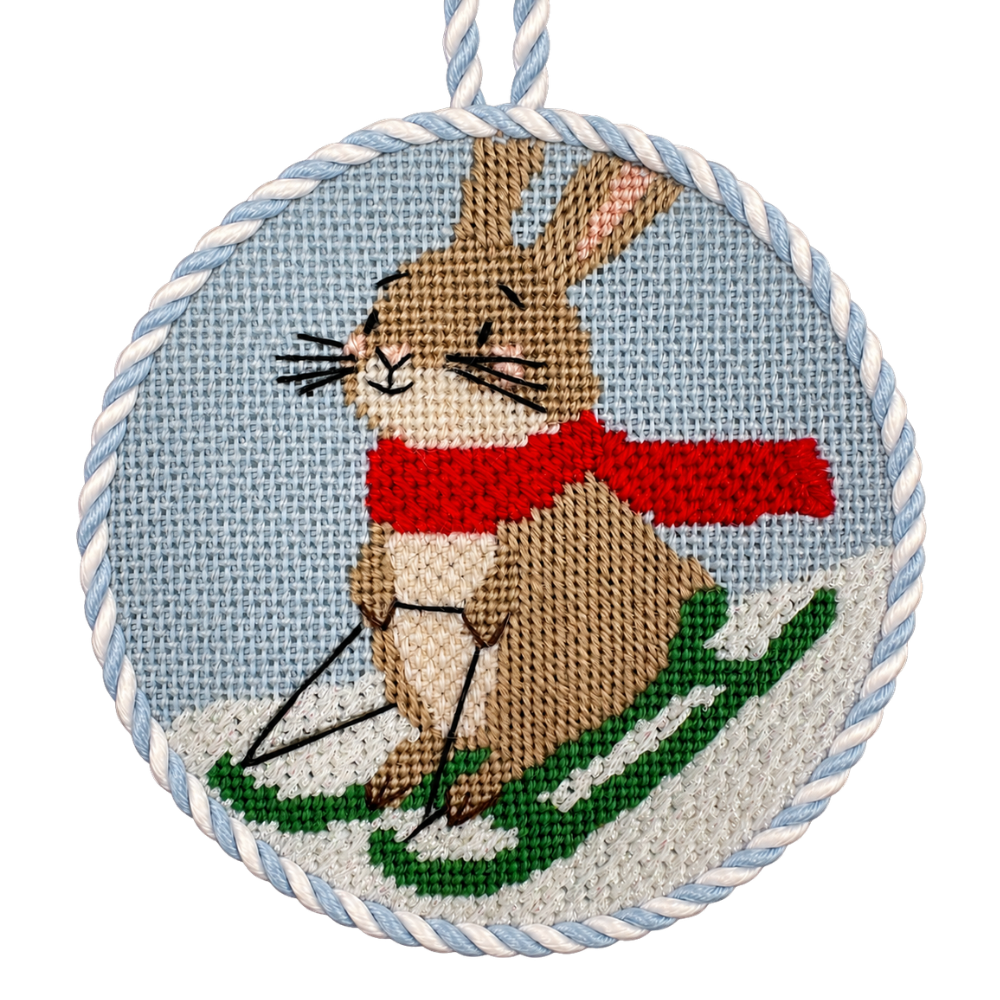 A needlepoint ornament of a hare on a sled