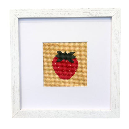 Framed needlepoint strawberry on a white background
