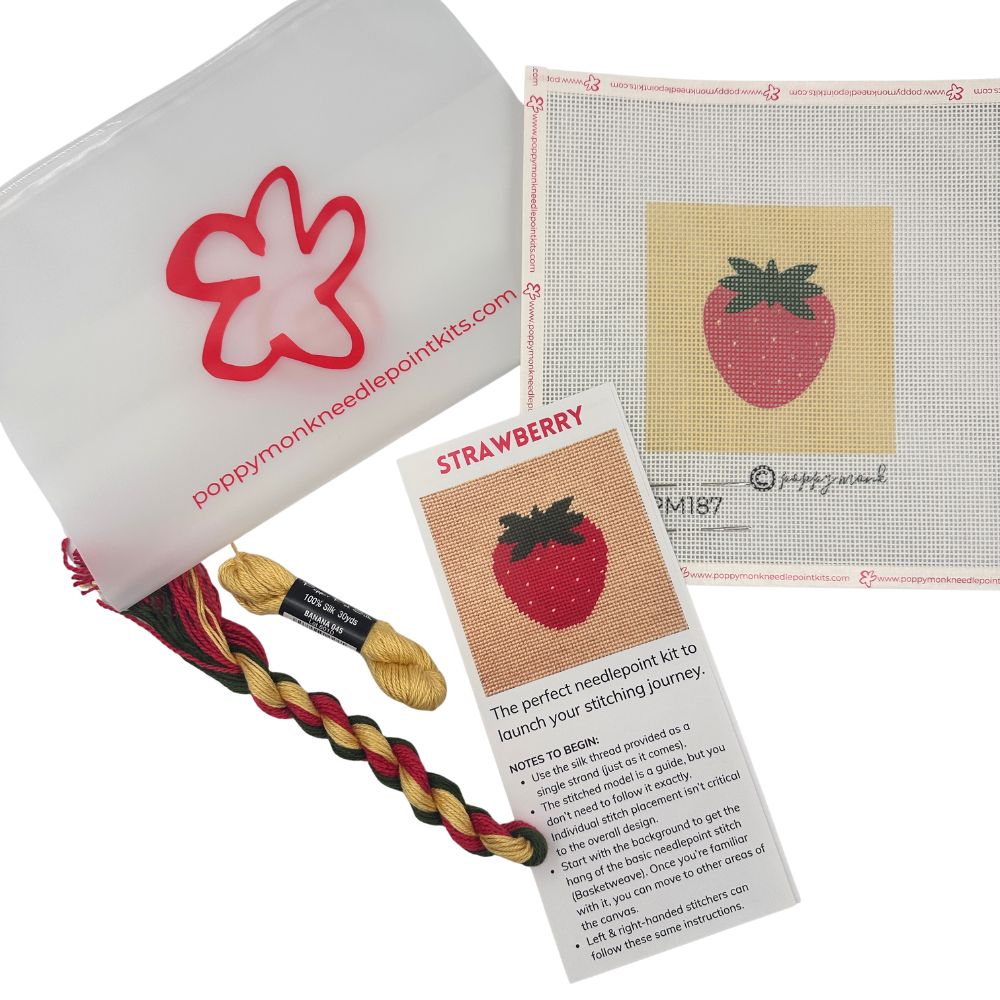 Needlepoint kit with strawberry design, yarn, and instructions on a white background