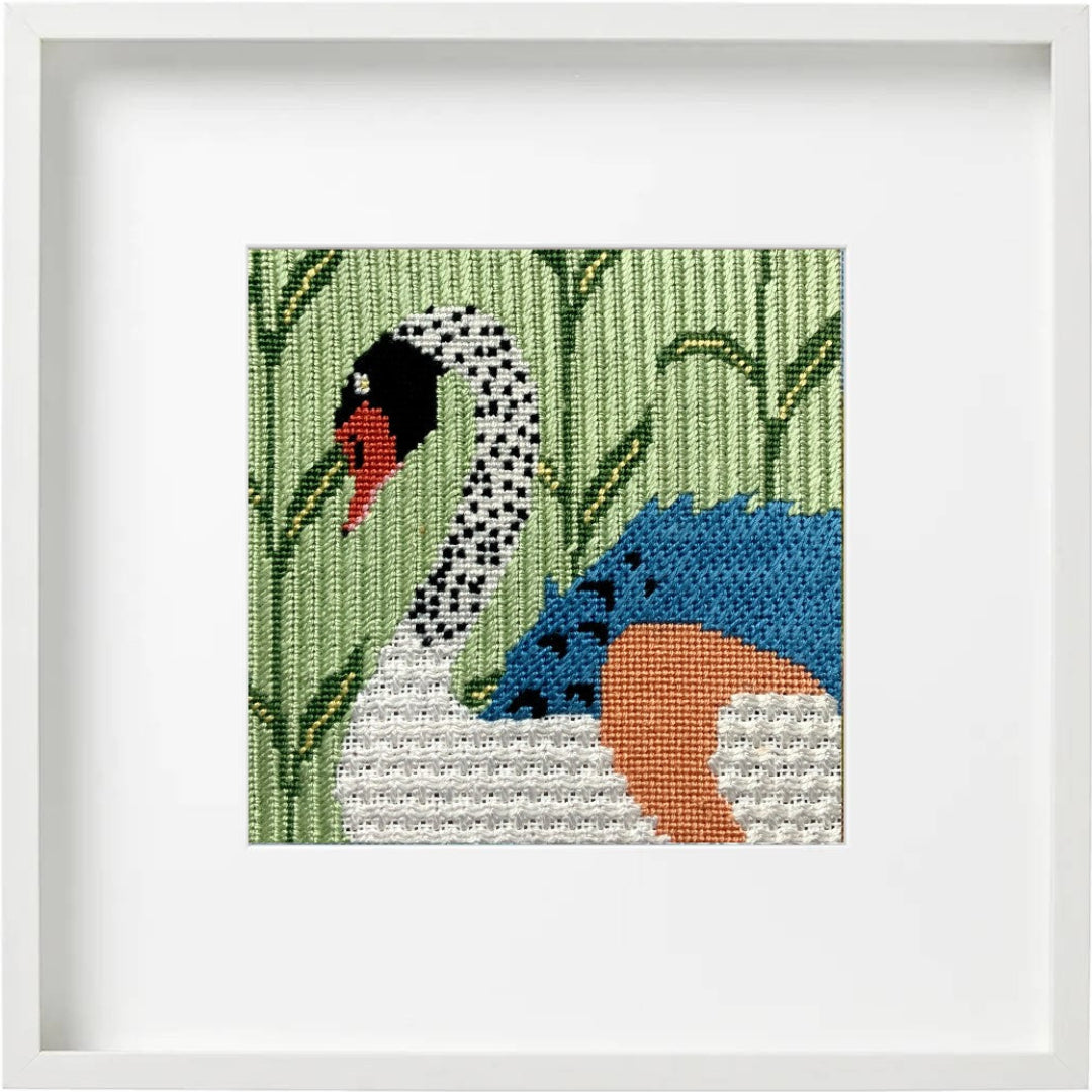 Framed needlepoint artwork of a swan on a green background