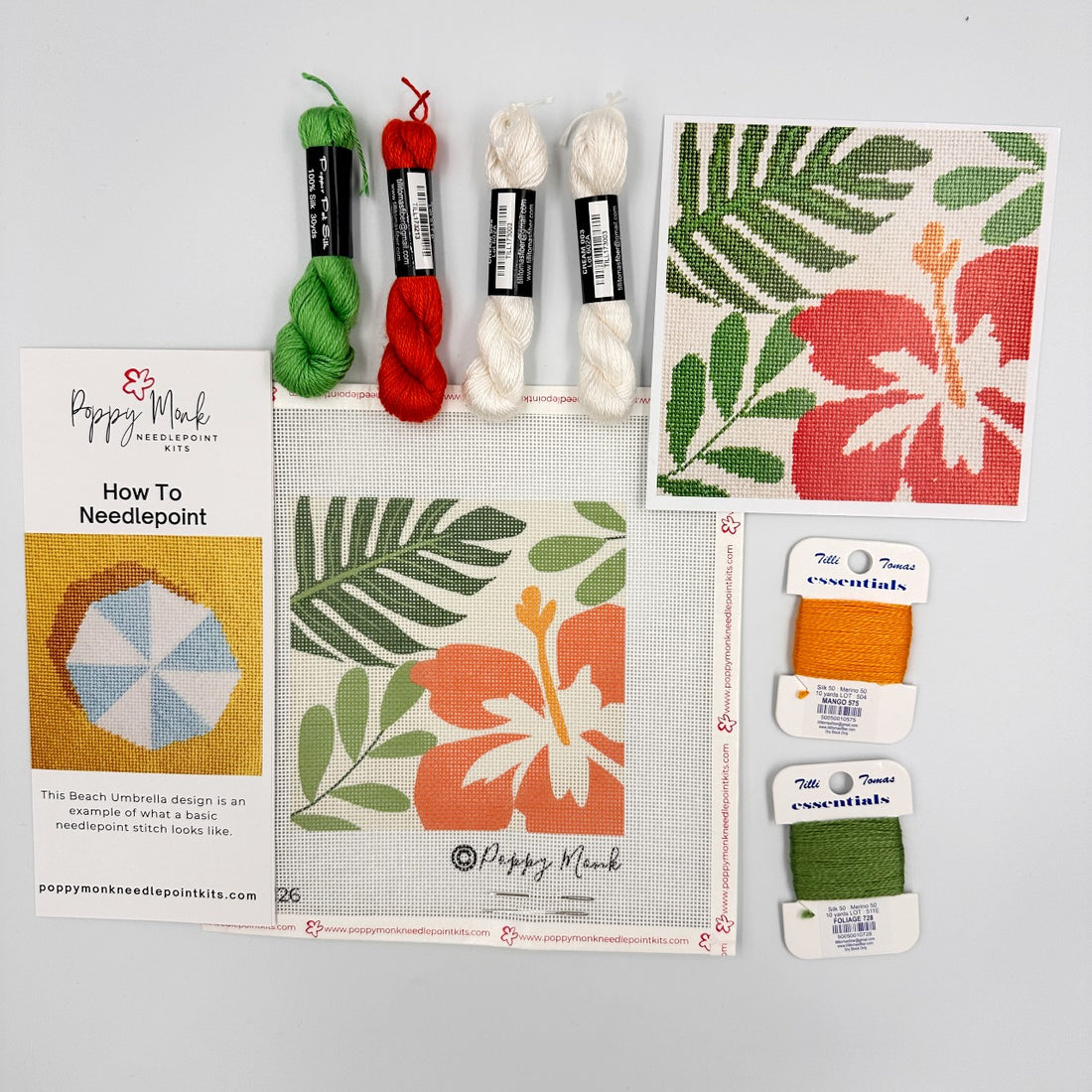 Needlepoint kit with yarn, canvas, and tools on a gray background