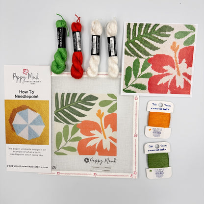 Needlepoint kit with yarn, canvas, and tools on a gray background