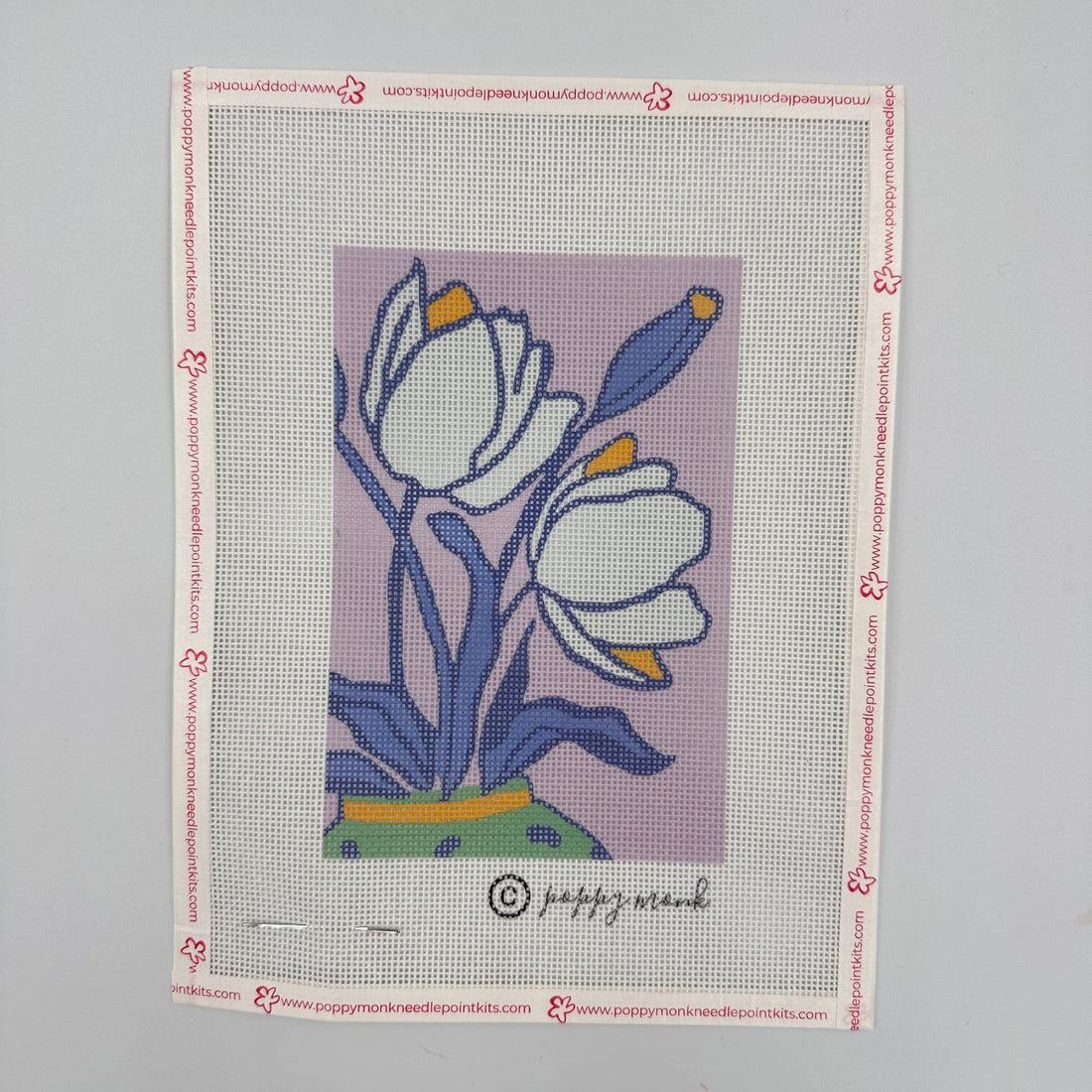 Needlepoint canvas with floral design on a gray background