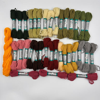 Assorted skeins of tapestry wool in various colors on a white background