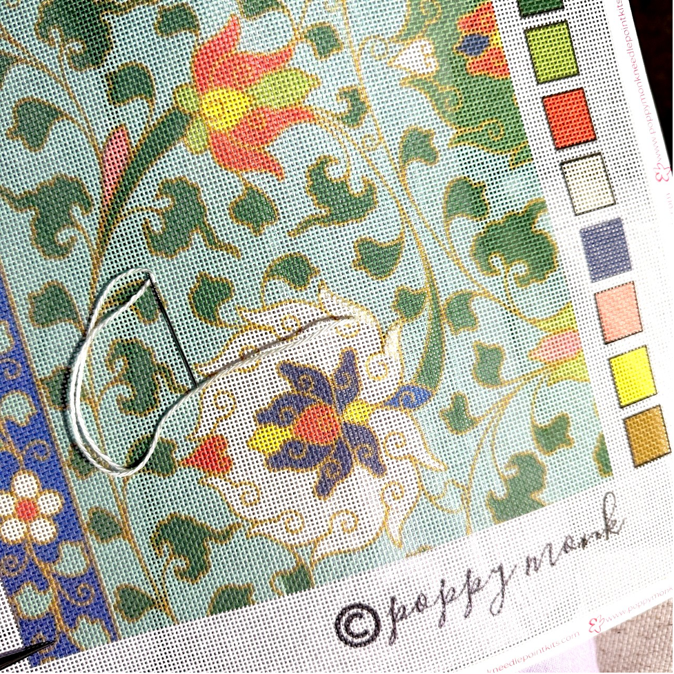 Needle and floral cross-stitch pattern on fabric with color swatch