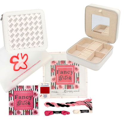 A craft kit featuring a white zippered pouch with a pink logo, a beige jewelry organizer box with a mirror, a printed fabric panel reading &