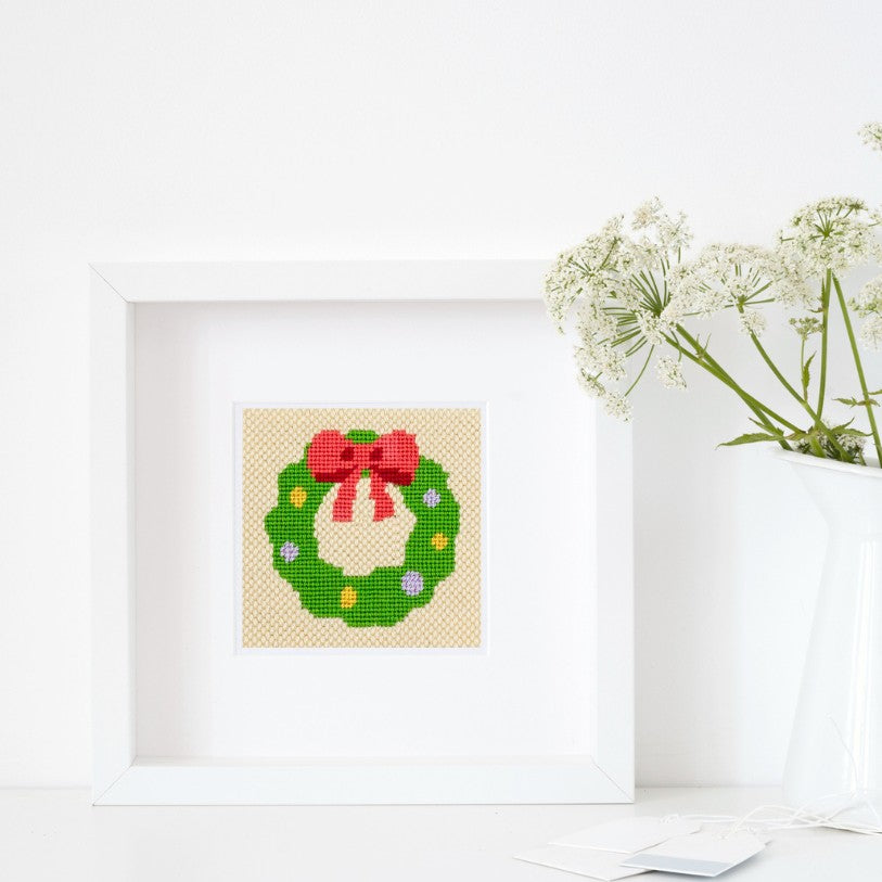 Holiday wreath needlepoint design in a white frame