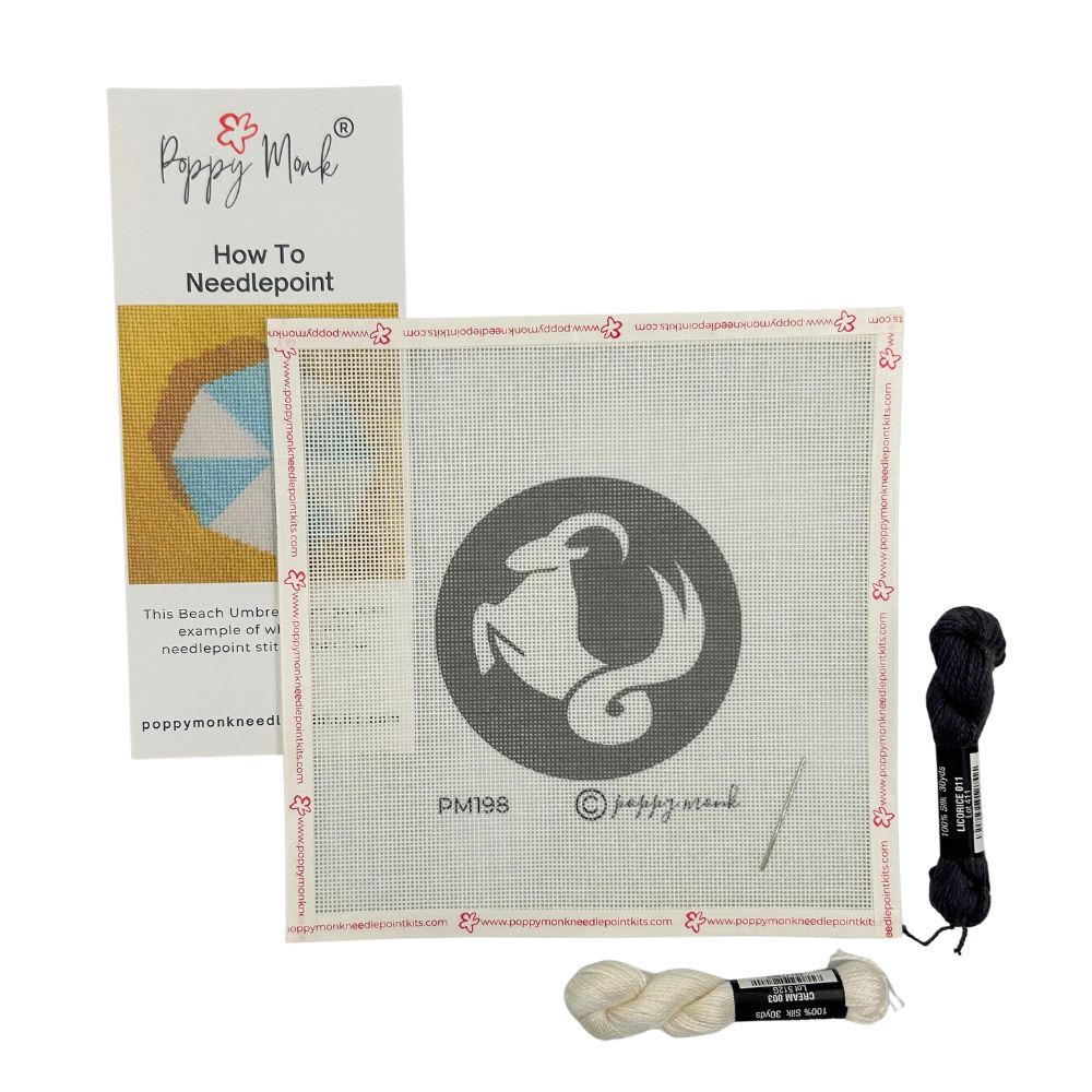 Needlepoint kit with Capricorn goat canvas, yarn, and instructions on a white background