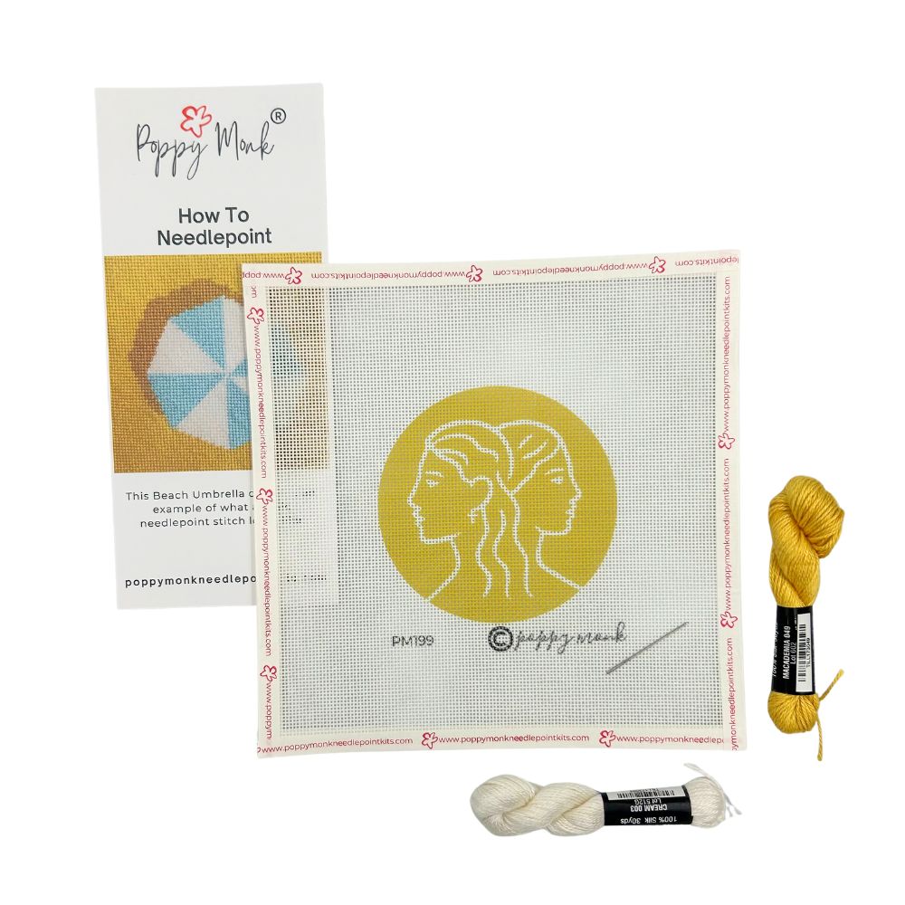Needlepoint kit with Gemini zodiac canvas, yarn, and instructions on a white background
