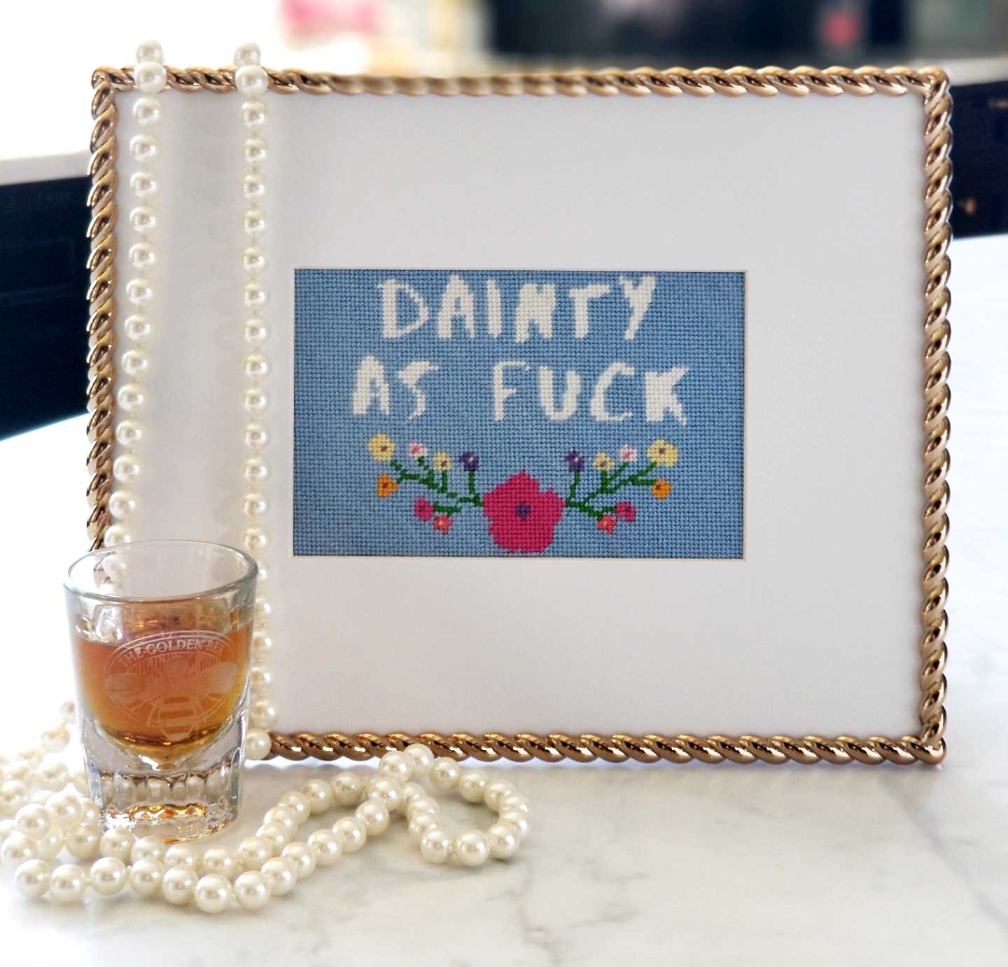 Dainty As Fuck needlepoint kit with silk threads, shown in a gold frame.